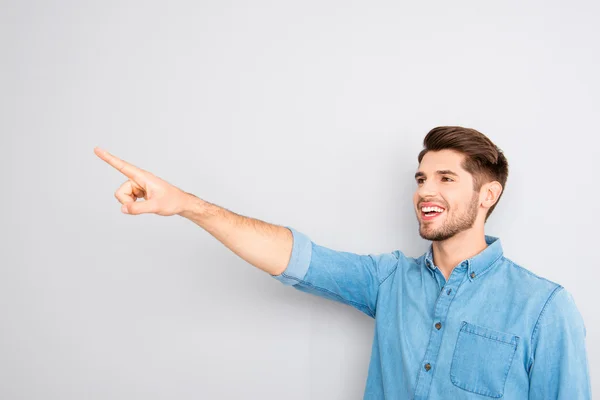 Knappe jongeman met vinger aan te wijzen en smth tonen — Stockfoto