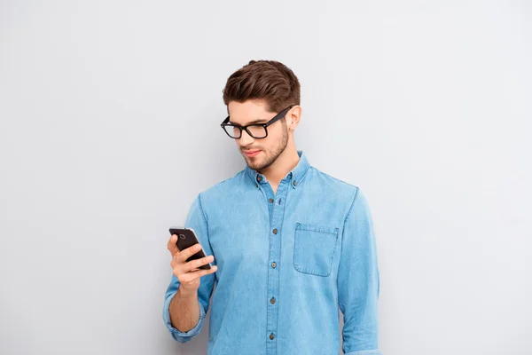 전화에서 메시지를 읽는 안경에 젊은 남자의 초상화 — 스톡 사진