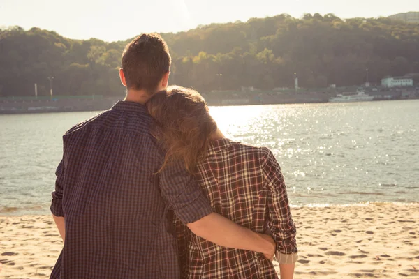 Vista trasera del joven abrazando a su novia en la playa —  Fotos de Stock