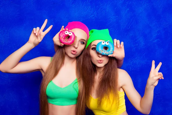 Krásné mladé ženy držící barva donutes očima — Stock fotografie
