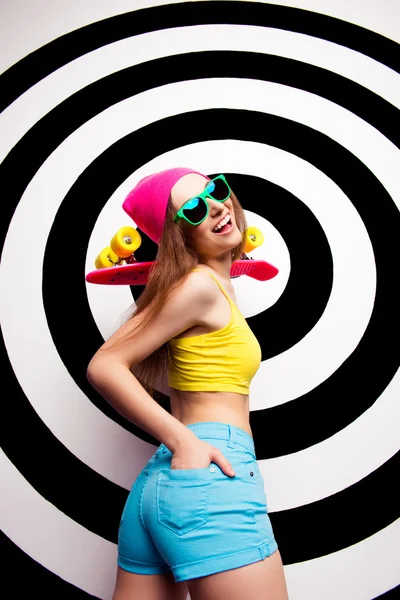 Mujer alegre en gafas con la espalda bien formada celebración de monopatín —  Fotos de Stock