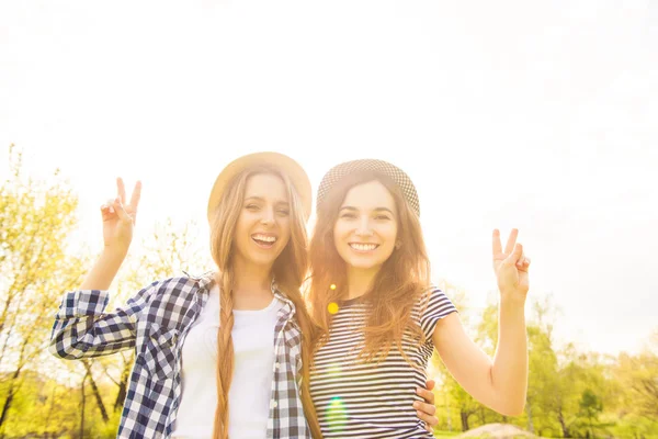 Ganska skrattande flickor i park gestikulerande med två fingrar — Stockfoto