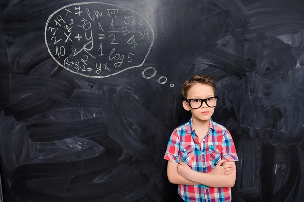 Young schoolboy in glasses at a loss on the background of chalkb — Stock Photo, Image