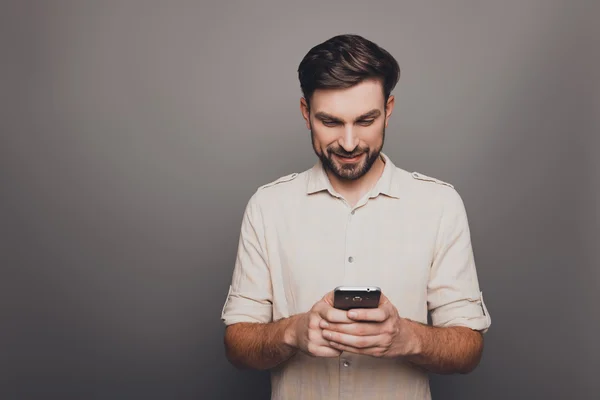 Felice giovane uomo digitando sms su sfondo grigio — Foto Stock