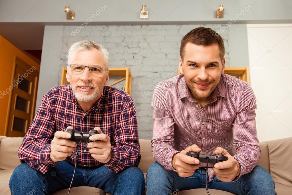 Happy man and his father playing video games while sitting on so