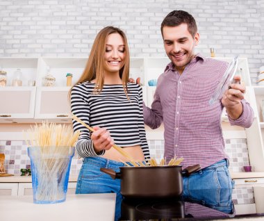 Happy young couple in love  boiling  pasta in the kitchen  clipart