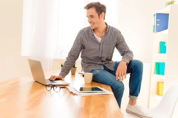 Hombre feliz con taza de café y portátil sentado en la mesa — Foto de Stock