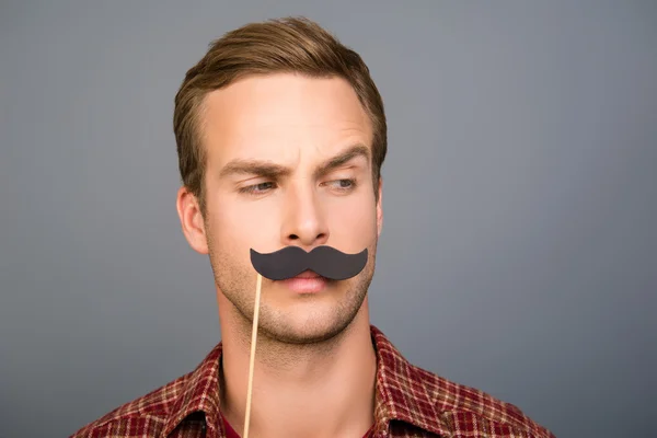 Portrait of pretty young man with paper mustache on gray backgro — Stock Photo, Image