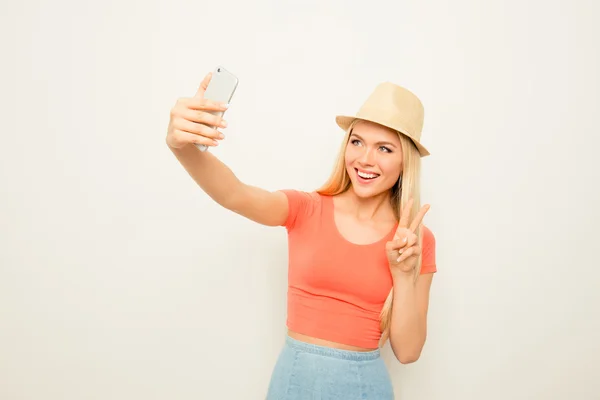 Cheerful happy woman making photo on smartphone and gesturing — Stock Photo, Image