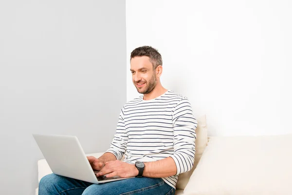 Portret van gelukkig knap man zittend op de Bank en typen op la — Stockfoto