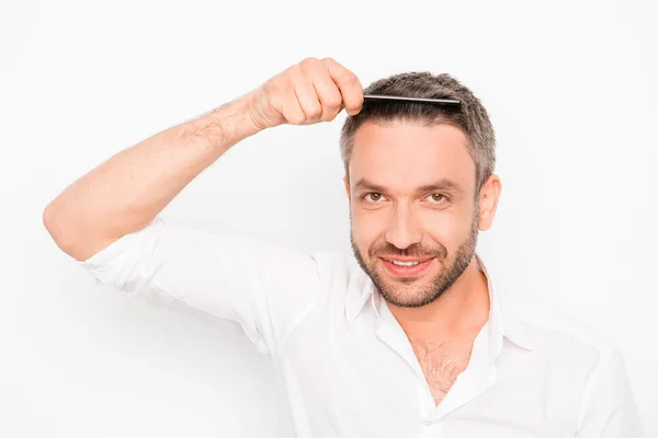 Homem atraente penteando seu cabelo no fundo branco — Fotografia de Stock