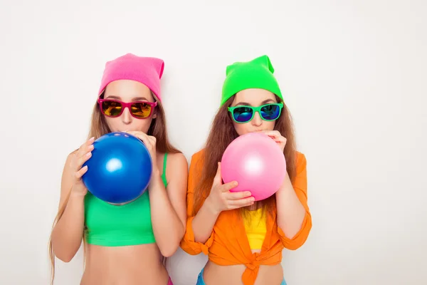 Πορτρέτο των δύο κοριτσιών hipster σε ποτήρια φυσώντας μπαλόνια — Φωτογραφία Αρχείου