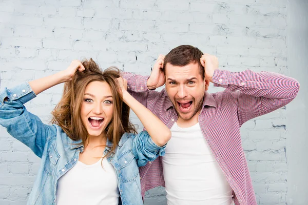 Portrait of young man and woman screaming and touching hair — Stock Photo, Image