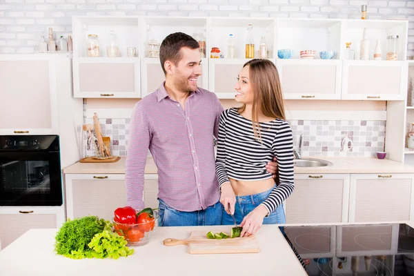 Smilling szerető pár vágás cuumbers a konyhában, és saláta — Stock Fotó