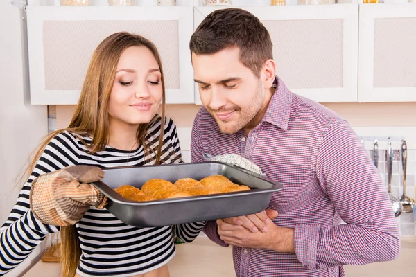 Jong koppel in liefde ruiken gebakken taarten in de keuken — Stockfoto