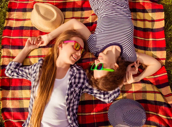 Top view of two happy girls in spectacles lying on plaid — Stock Photo, Image