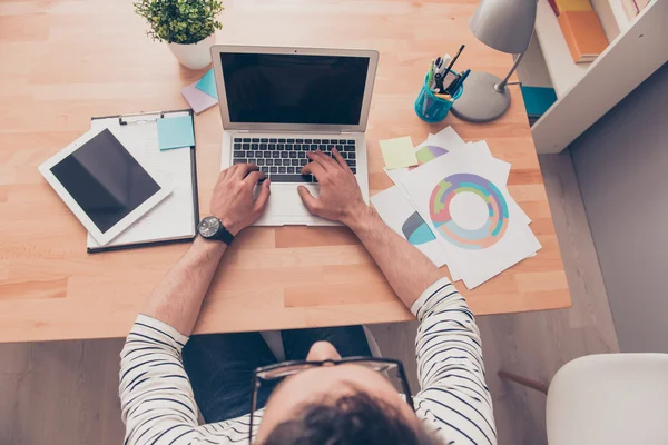 Ansicht von oben: Geschäftsmann erledigt Papierkram und tippt auf Laptop — Stockfoto