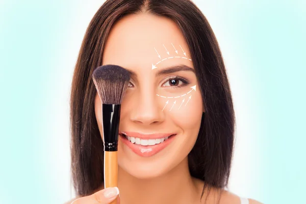 Primer plano retrato de mujer bonita sosteniendo cepillo de maquillaje cerca de ojo — Foto de Stock