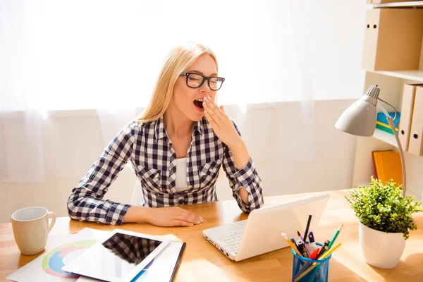 Mujer joven cansada en gafas bostezando después del trabajo con el ordenador portátil — Foto de Stock