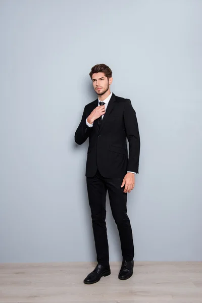 Full length portrait of young businessman in black suit correcti — Stock Photo, Image