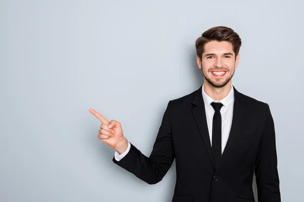 Handsome young businessman in black suit pointing with finger — Stock Photo, Image