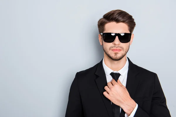 Портрет молодого успешного человека в очках, исправляющего галстук — стоковое фото