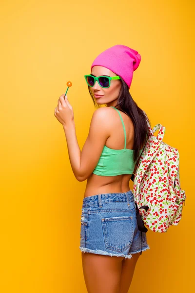 Aantrekkelijke schattig hipster meisje met rugzak likken lolly sta — Stockfoto