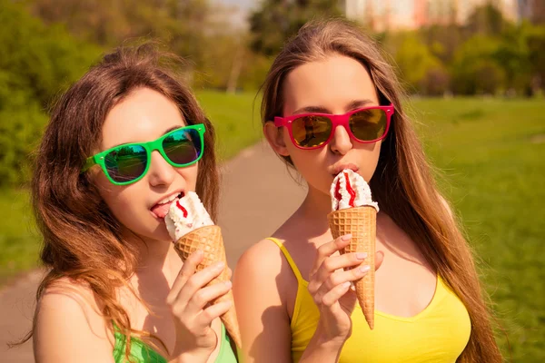 Портрет двух молодых сестер в очках, кушающих мороженое — стоковое фото