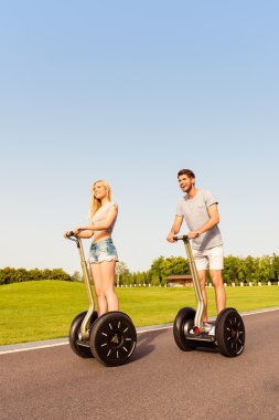 Young happy tourist couple in love riding segway clipart
