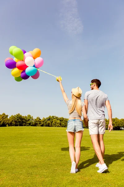 Вид ззаду на двох друзів, що ходять у парку з повітряними кулями — стокове фото