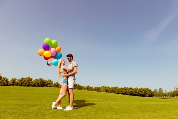 Två glada unga älskare med ballonger embracing i parken — Stockfoto