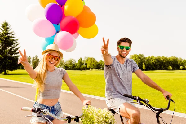 Homem feliz e mulher andando de bicicleta e gesticulando com os dedos — Fotografia de Stock