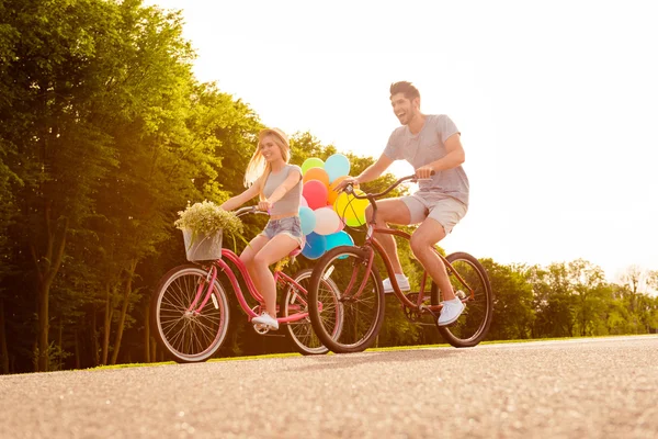 Happy young lovely couple in love with balloons riding bicycles — Stock Photo, Image