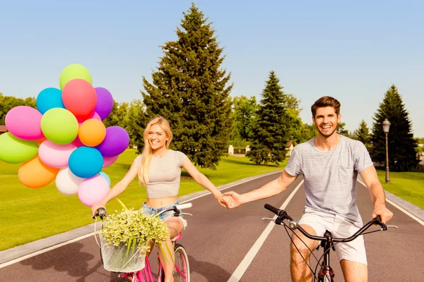 Happy young lovely couple in love cycling and holding hands — Stock Photo, Image