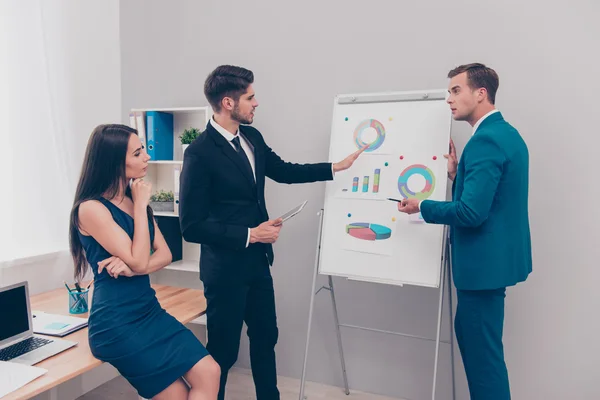 Giovane uomo che mostra diagramma su flipchart ai suoi colleghi — Foto Stock