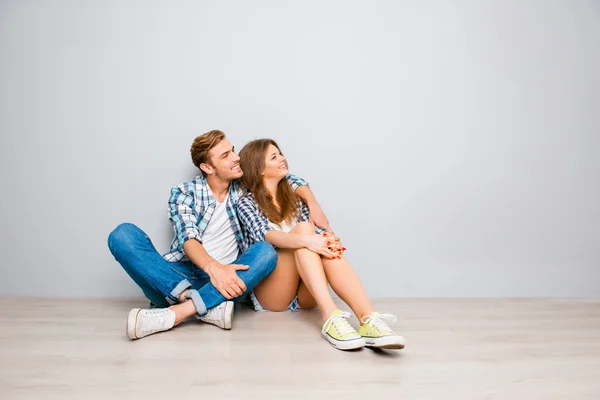 Vzrušený muž a žena sedí na podlaze a při pohledu na co — Stock fotografie