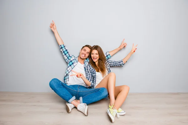 Happy cheerful lovers sitting on floor and gesturing with raised — Stock Photo, Image