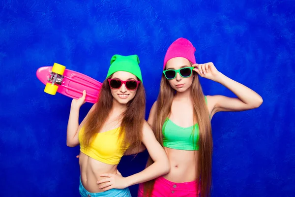 Souriant femmes patineuses sexy dans des chapeaux et des lunettes avec skate — Photo