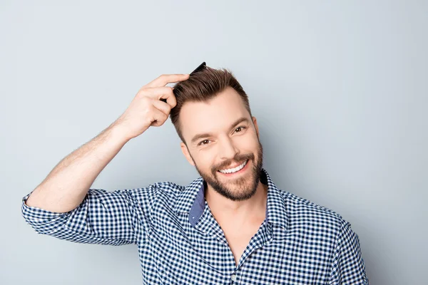 Portrait of happy smiling handsome guy combing his hair — Stock Photo, Image