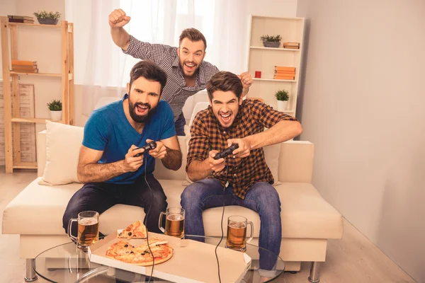 Победа! взволнованные веселые мужчины играют в видеоигры с пивом и пи — стоковое фото