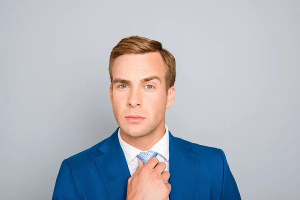 Retrato de hombre de negocios guapo en traje azul corrigiendo su corbata — Foto de Stock