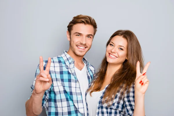 Fröhliches, glückliches junges Paar zeigt zwei Finger — Stockfoto