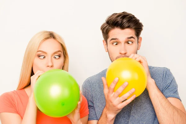 Twee grappige liefhebbers opblazen van ballonnen voor viering en grimaci — Stockfoto