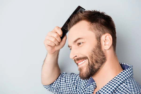 Portrait of handsome cheerful young man combing his hair — Stock Photo, Image