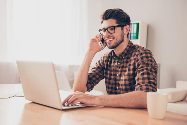 Fiatal üzletember beszél telefonon munka közben a laptop — Stock Fotó