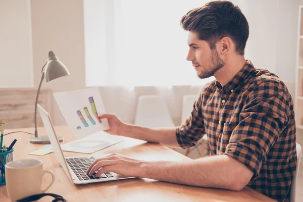 Zijaanzicht van de geconcentreerde jonge mens werken met laptop en diag — Stockfoto