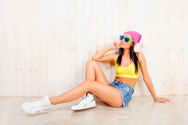 Hipster girl in pink cap and glasses siting on floor — Stock Photo, Image