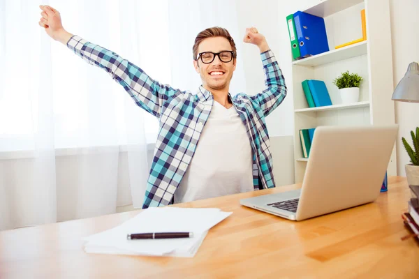 Bel homme souriant dans des lunettes étirant les mains après avoir travaillé d — Photo