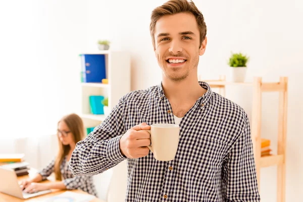 Χαμογελαστός άνθρωπος πίνει καφέ, ενώ ο Γραμματέας πληκτρολογώντας σε φορητό υπολογιστή — Φωτογραφία Αρχείου