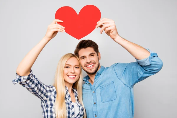 Young smiling family holding paper heart under head — Stock Photo, Image